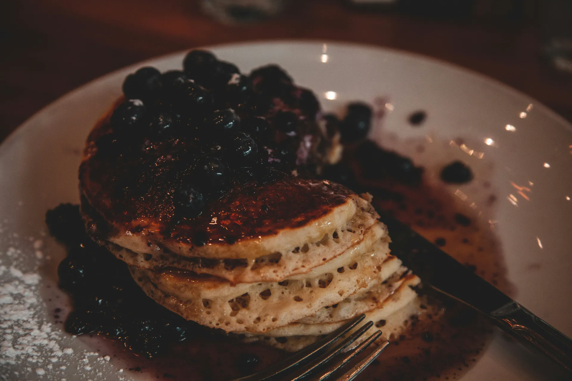 Stack of pancakes topped with fresh blueberries and syrup, perfect for a cozy breakfast.