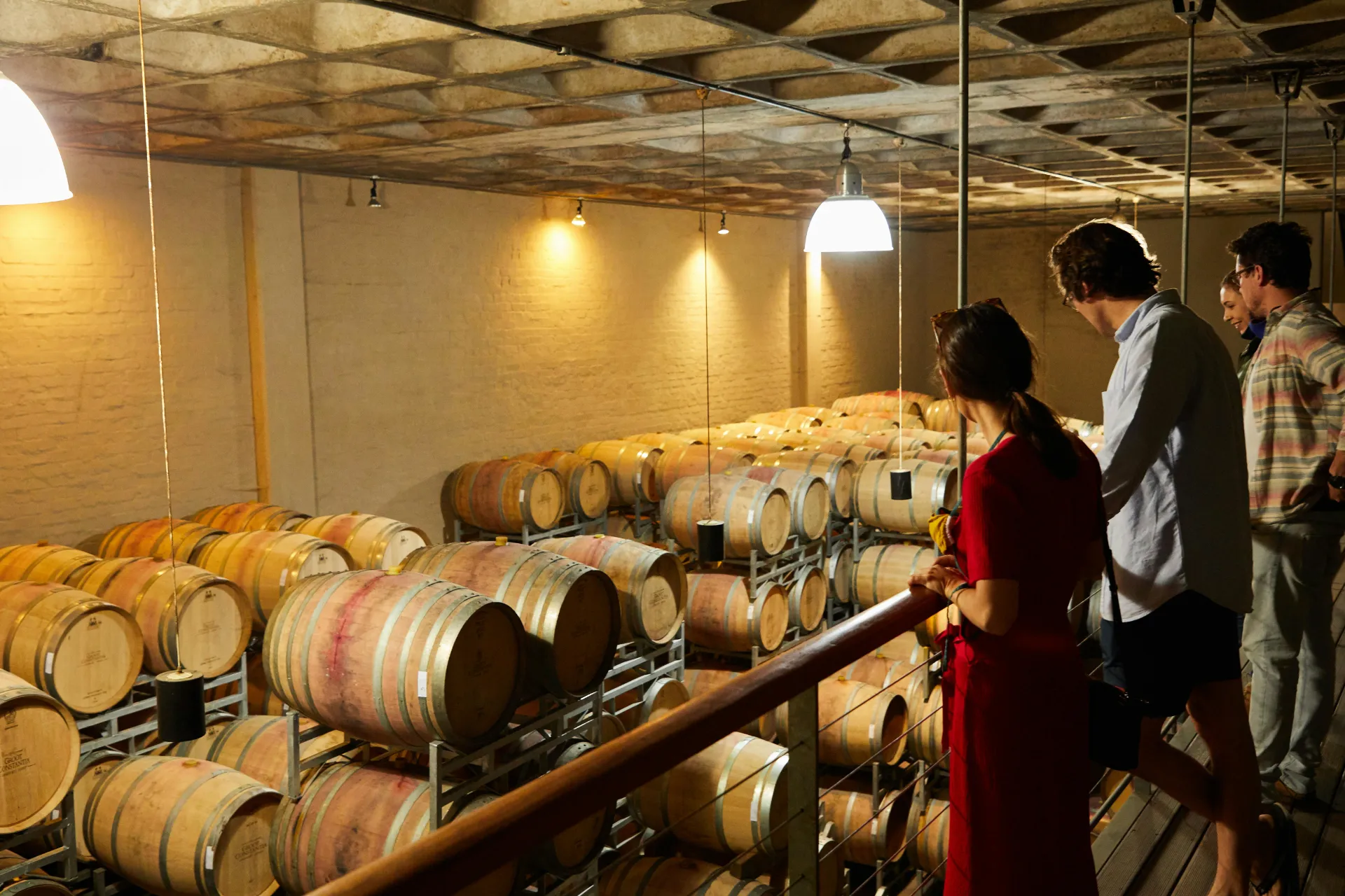 Group of people observing wine barrels in an indoor winery setting